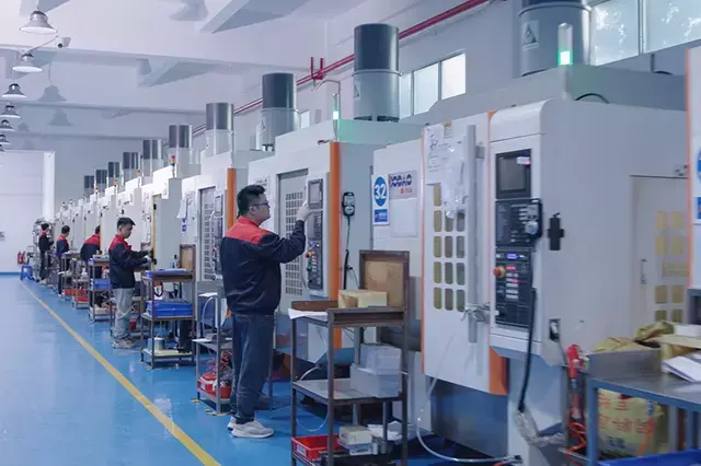 Row of vertical machining centres with operators in a blue-floored BOEN workshop