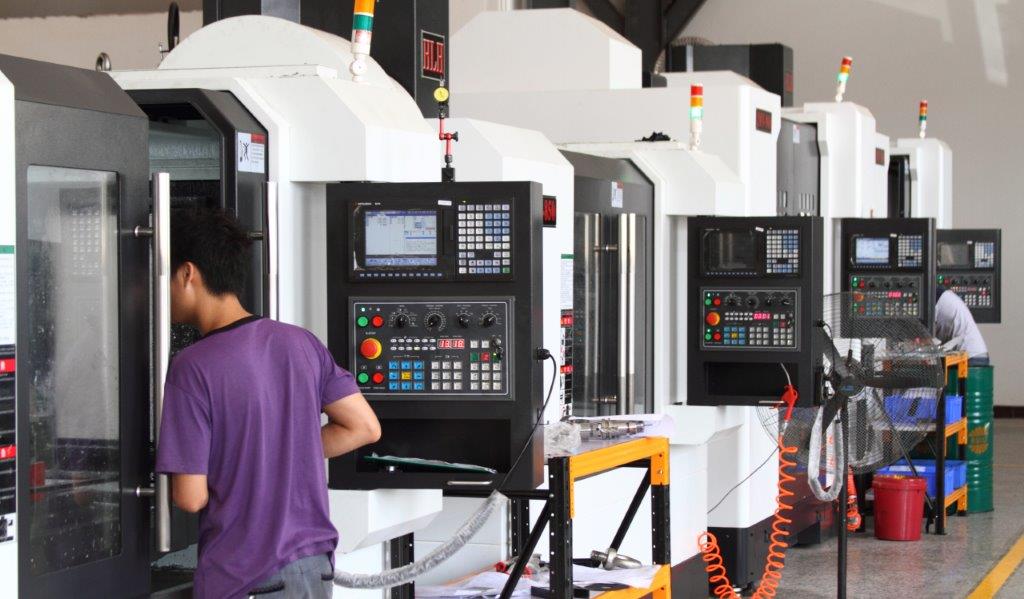 Row of CNC machining centers with an operator loading a machine