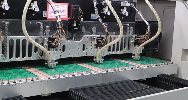 Machine spindles working over green circuit board panels