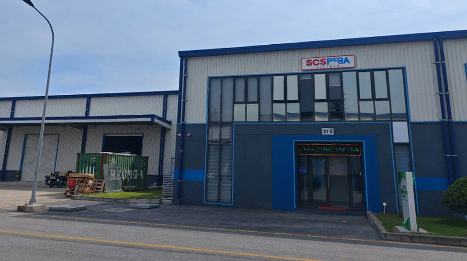 Exterior of a blue and grey factory building with an SCSPCBA Vietnam sign