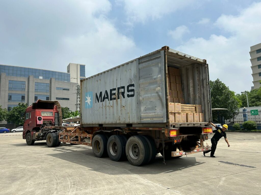 Shipping container on a truck, loaded with cartons, in a factory yard